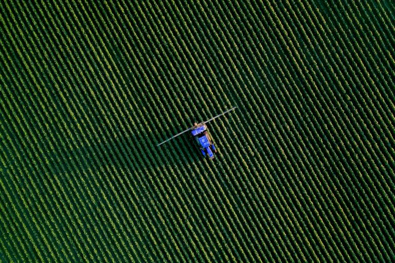 trator pulverizando lavoura — EPI para agronegócio e aplicação de defensivos